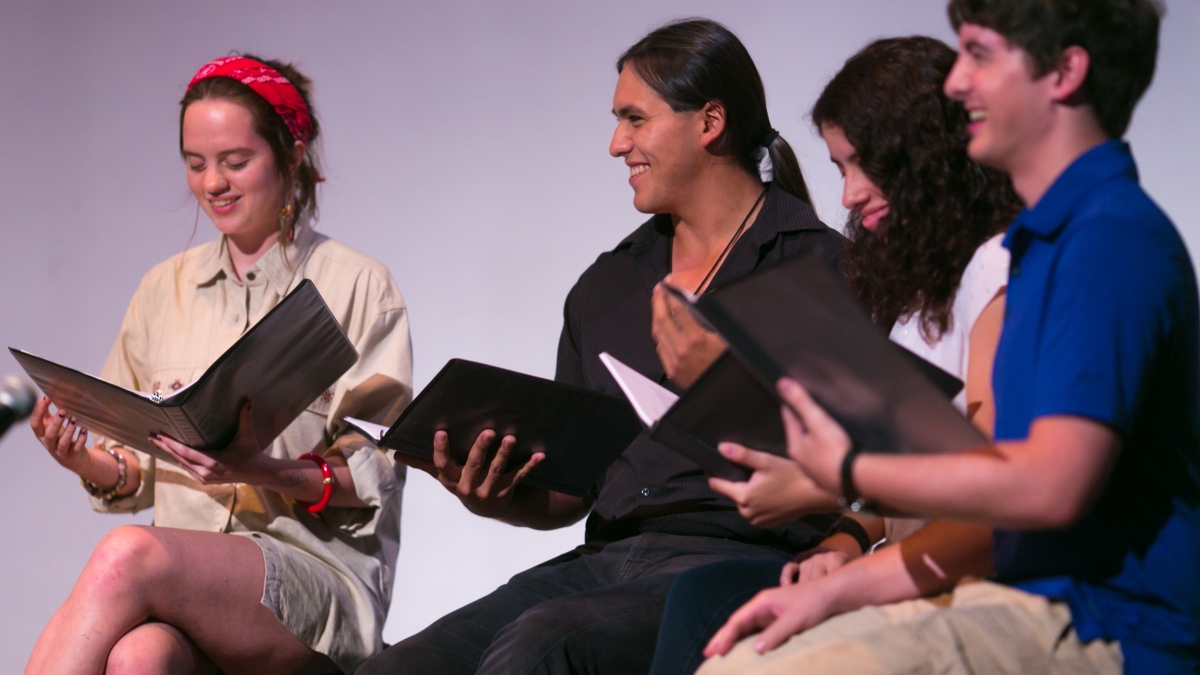 diverse group of people smiling and reading from a folder